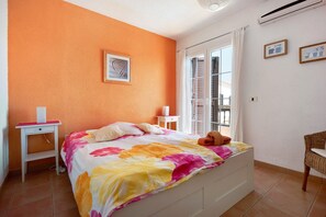 Una camera da letto con un letto, un comodino, una sedia e una finestra con tende.