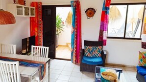 A dining area with a table and chairs, a television, and a view of the outside. - Casa Dos Ángeles with Mountain Views, Pool, Air Conditioning, Wi-Fi, Garden & Terrace (Arona)