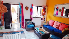 A room with a sofa, a chair, a dining table, and colorful curtains. - Casa Dos Ángeles: Mountain Views, Pool, AC, Wi-Fi, Garden & Terrace (Arona)