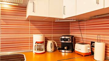 A kitchen with striped backsplash, a coffee maker, a toaster, and a kettle.