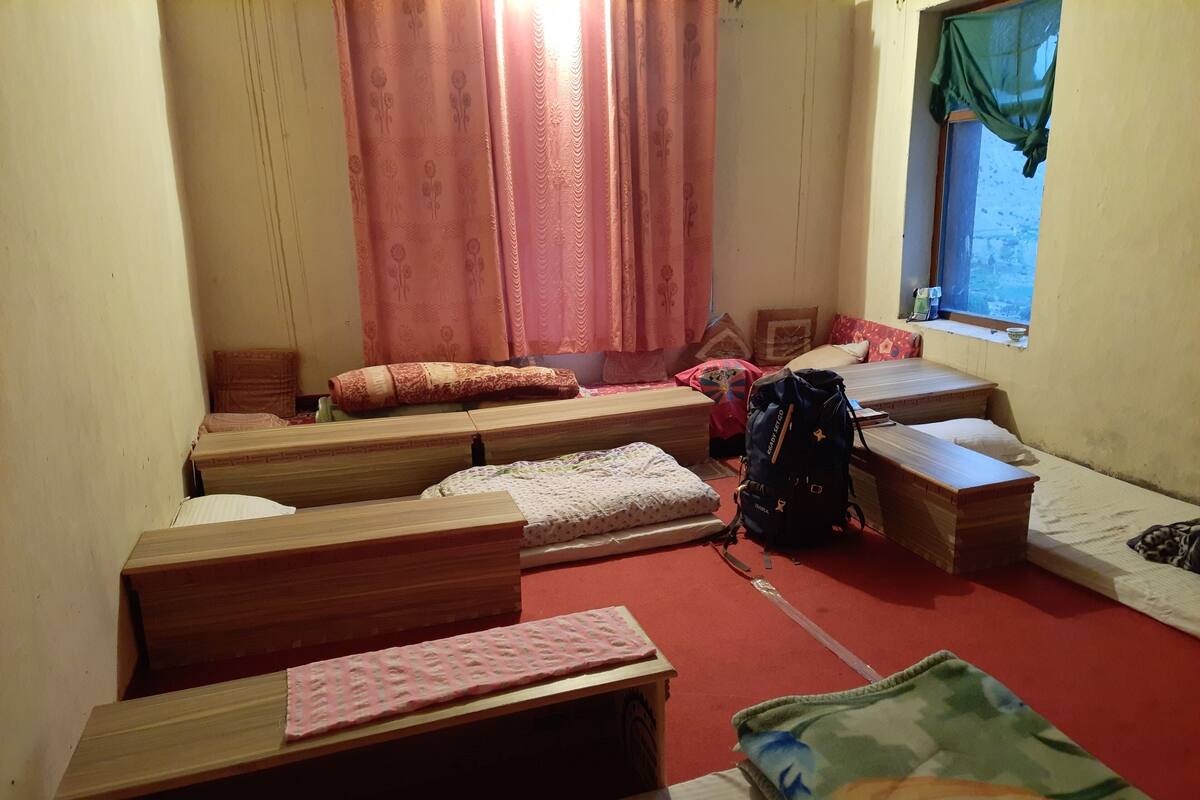 A dormitory room with bunk beds, a small window with a view, and a backpack on the floor.
