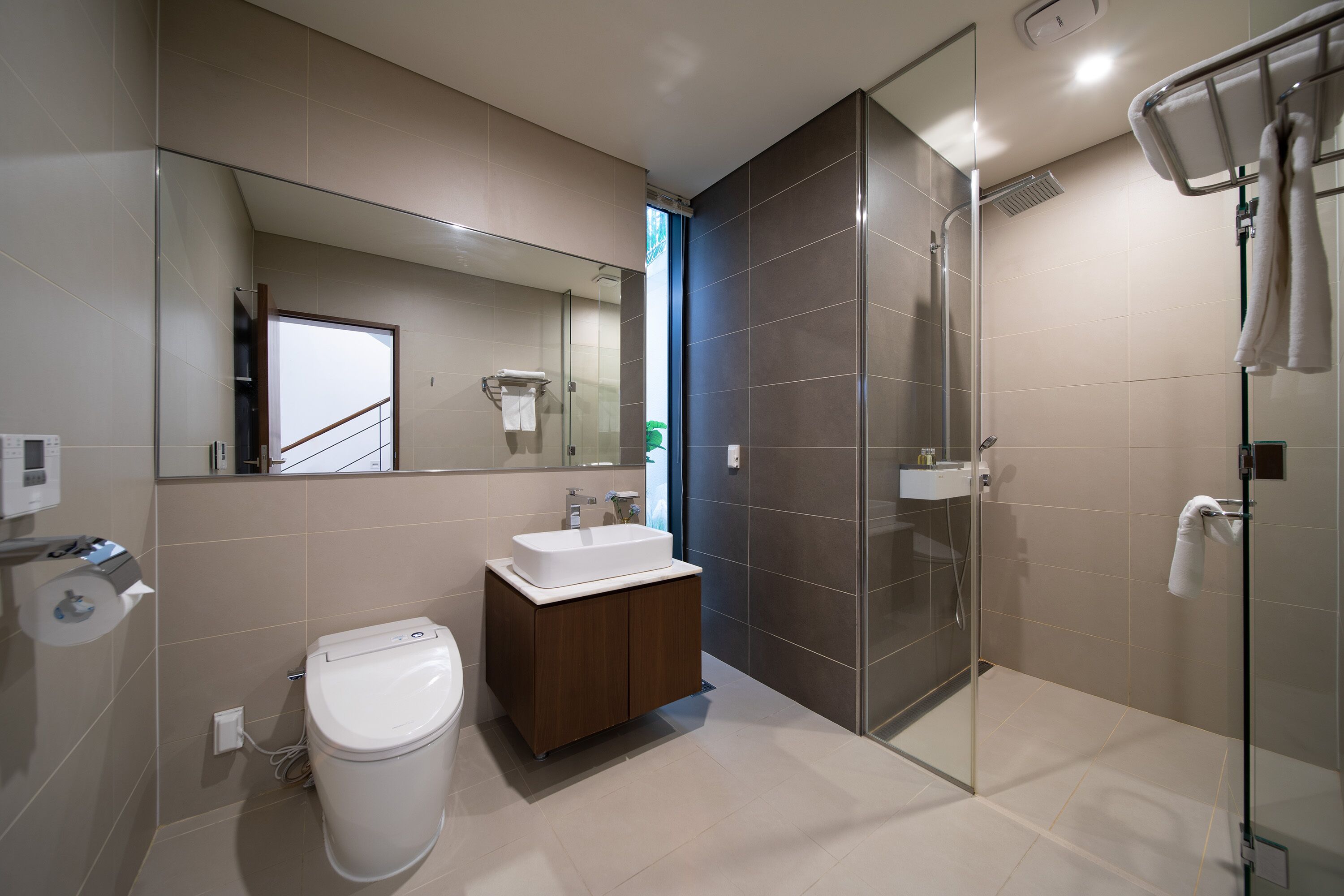 Un baño moderno con inodoro, lavabo y cabina de ducha de vidrio.