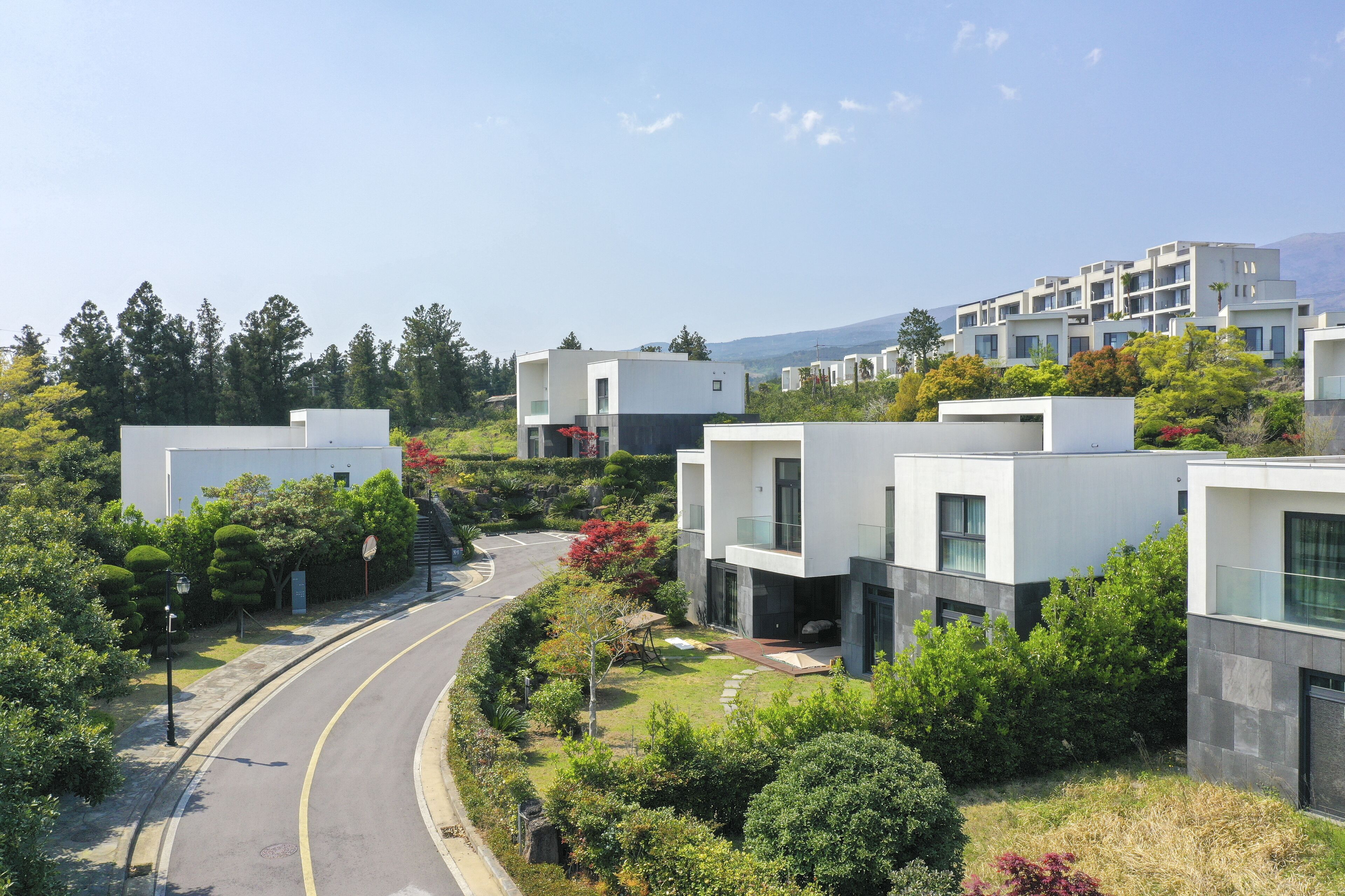 A modern residential area with contemporary buildings, a curved road, and lush greenery.