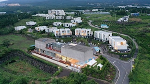 Un moderno resort con varias edificaciones, piscina y jardines bien cuidados.