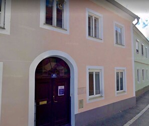 En bygning med en mørk hoveddør, hvor nummer 19 er angivet, flere vinduer og en lys facade.