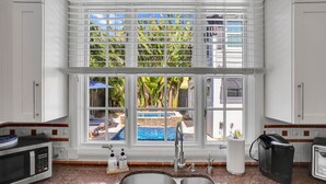 A kitchen with a large window, a double sink, and a coffee maker.