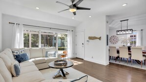 A spacious living room with a sofa, a dining area with a chandelier, and a ceiling fan.