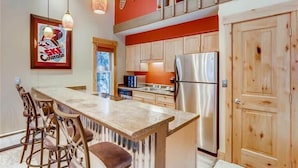 A kitchen with a central island, wooden cabinets, a stainless steel refrigerator, and pendant lights. - Timbernest Condo - 2 BDR Walk to Downtown & Lift! (Breckenridge)