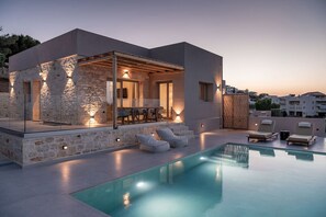 Une maison moderne dotée d’une piscine, de murs en pierre et d’un espace salon extérieur.