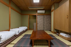 A traditional Japanese-style room with tatami mats, a wooden table, and futons. - Tabist Business Hotel Marutomi Takamatsu Kagawa (Takamatsu)