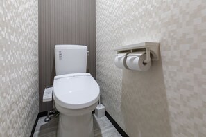 A modern bathroom with a toilet, a toilet paper holder, and a wall-mounted control panel. - Tabist Business Hotel Marutomi Takamatsu Kagawa (Takamatsu)