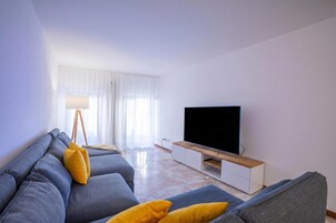 A modern living room with a sofa set, a flat-screen TV, and a floor lamp.