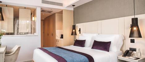A modern hotel room with a large bed, bedside tables, a desk, and a chair.