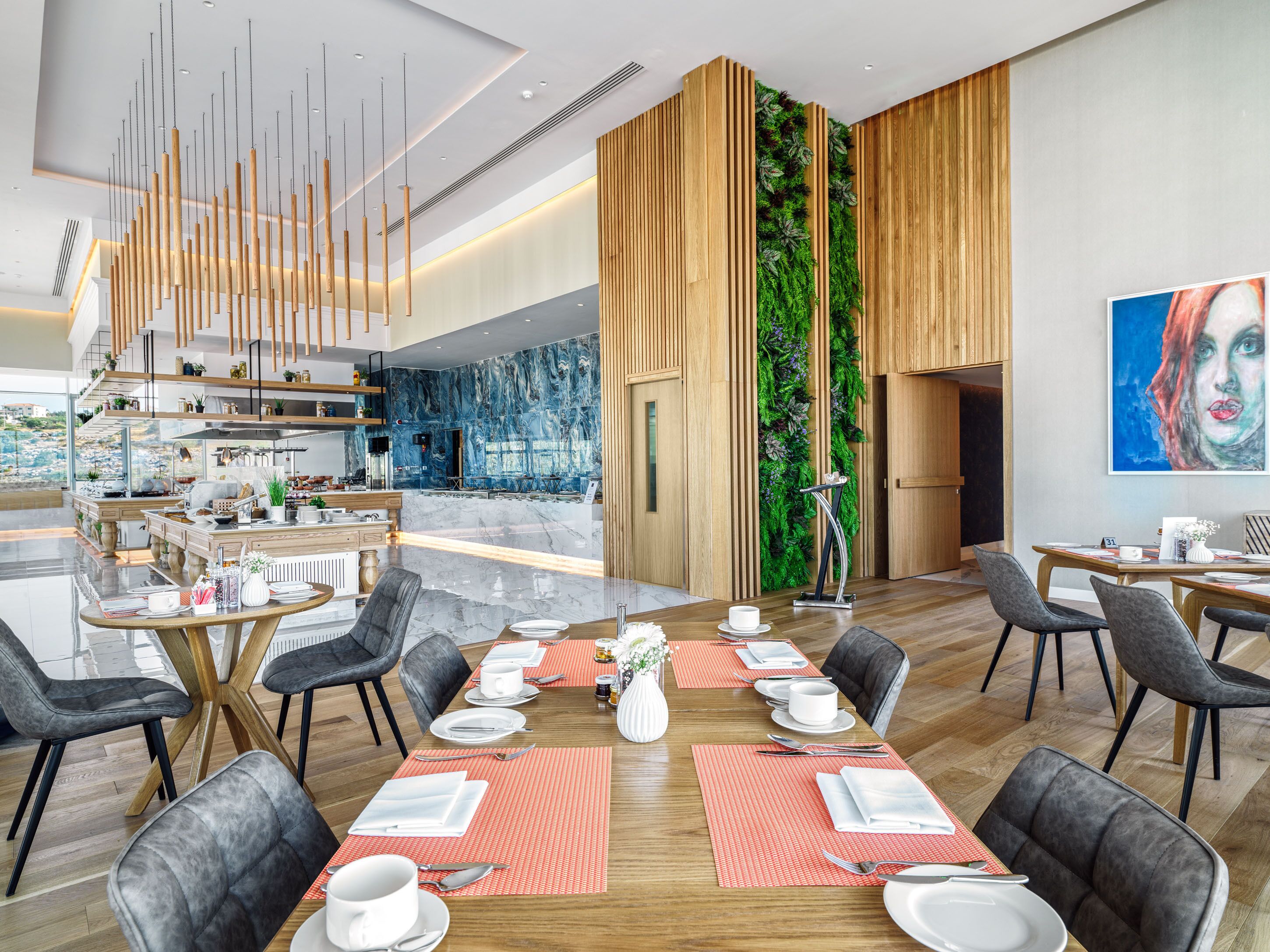 A modern dining area with a long table set for a meal, surrounded by chairs.