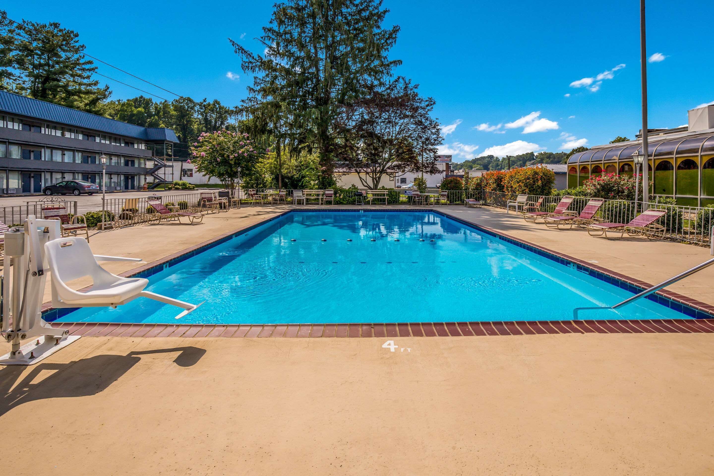 A rectangular swimming pool with a clear blue water surface, surrounded by a brick deck.