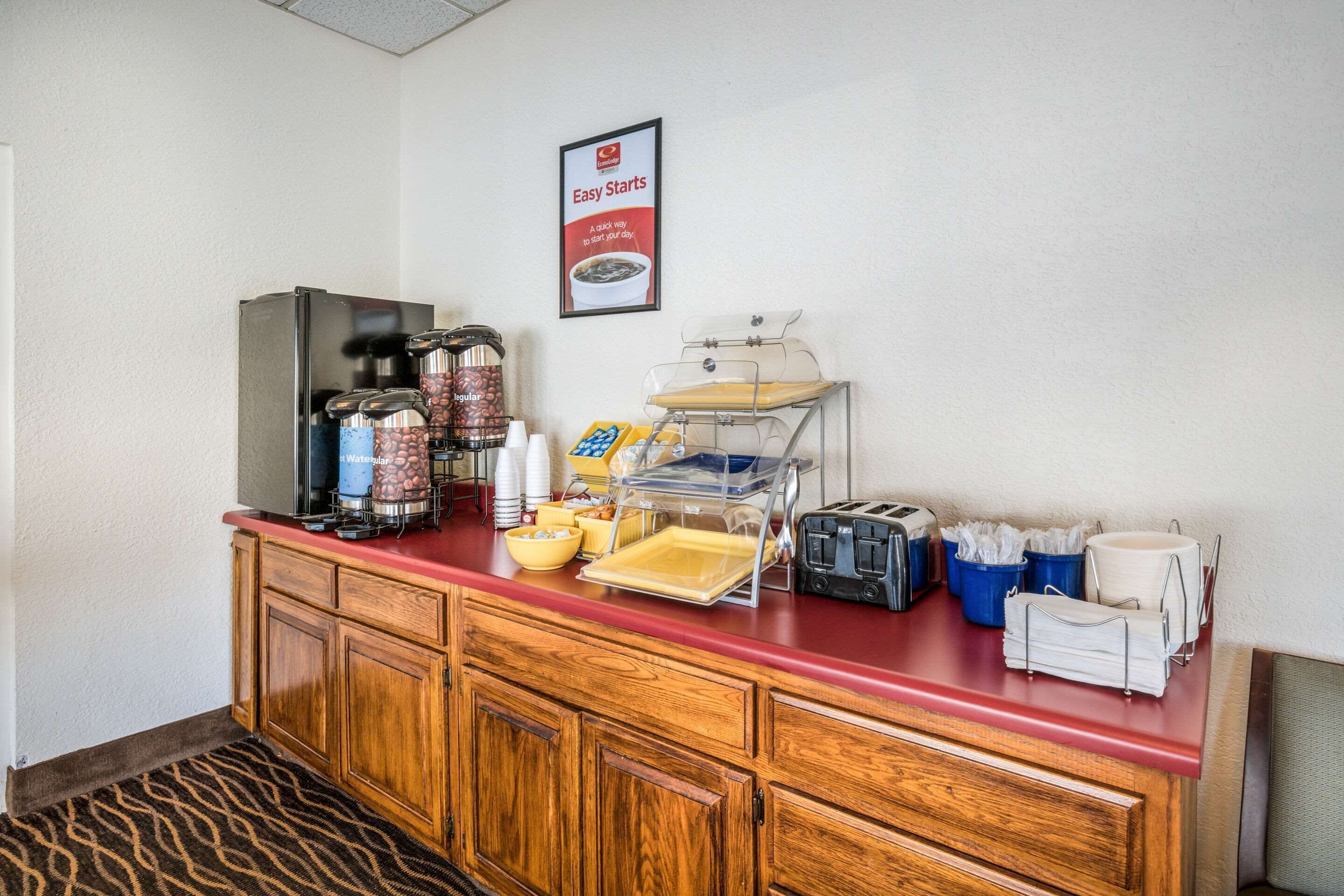 A hotel breakfast bar with a coffee maker, coffee urns, a toaster, and a sign advertising "Easy Starts".