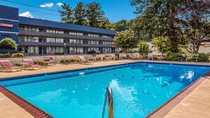 A swimming pool with lounge chairs and a building in the background. - Suburban Studios Middlesboro (Middlesboro)