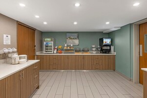 Uma cozinha moderna com armários de madeira, bancada branca e uma cafeteira.