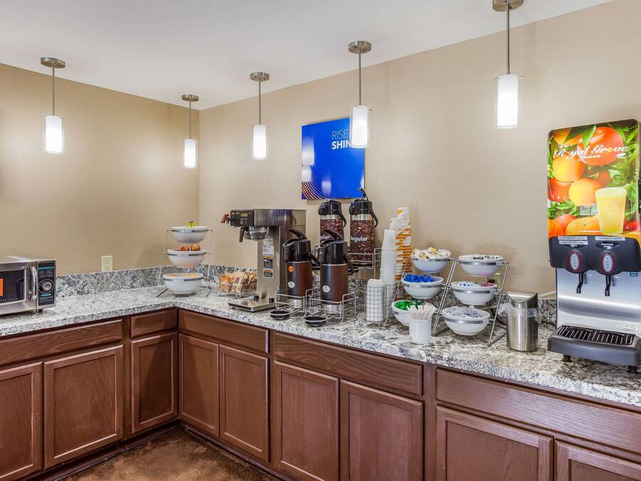 Una cocina de hotel con una estación de café, microondas y diferentes recipientes de comida.