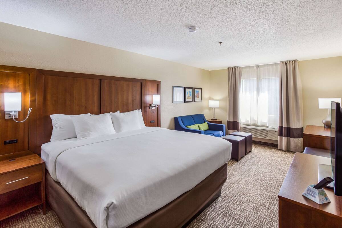 A hotel room with a large bed, a desk, a chair, and a television.