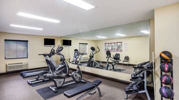 A gym with exercise equipment, a mirror, and a wall-mounted dumbbell rack.