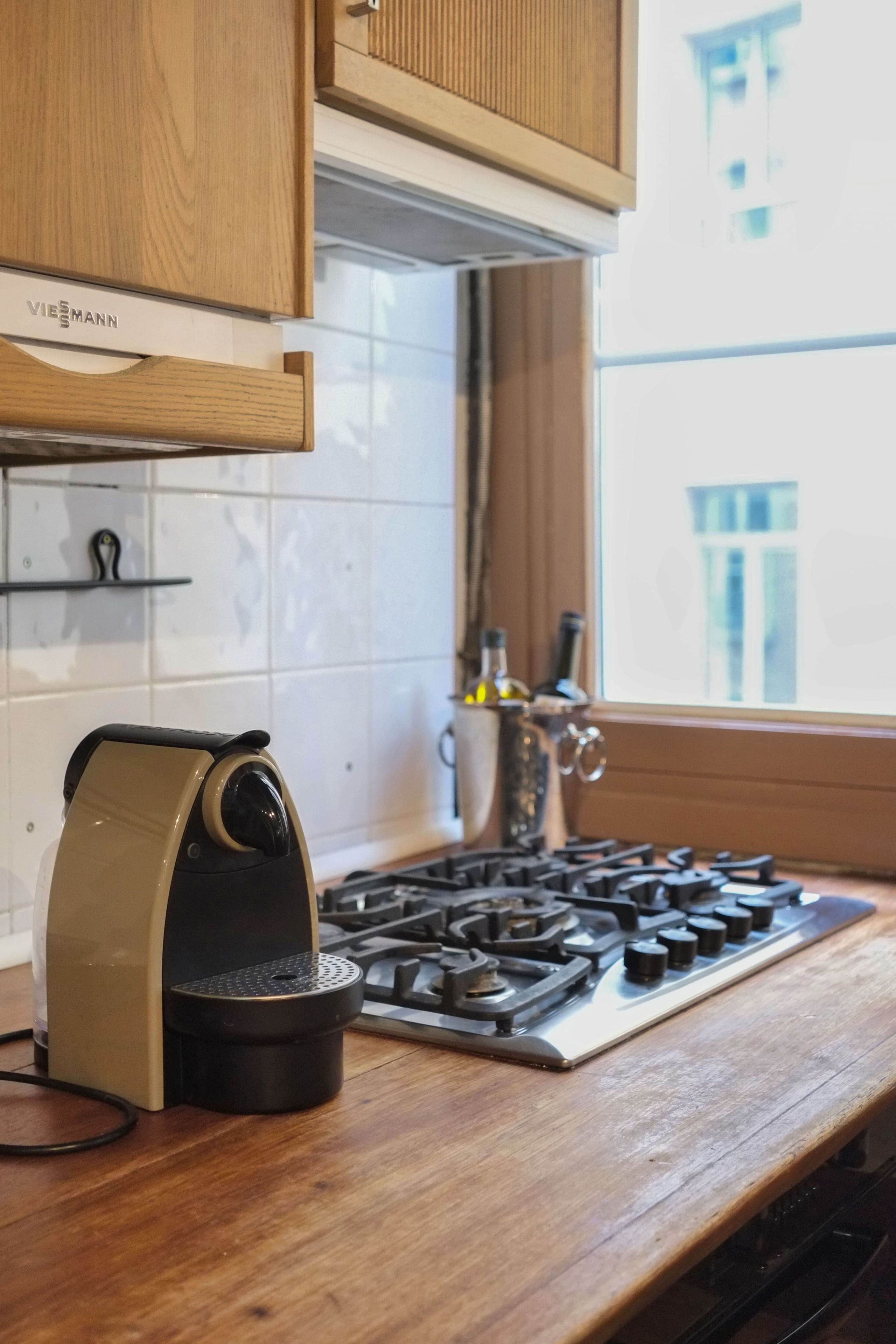 Une cuisine équipée d’une cuisinière, d’une machine à café et de meubles de rangement en bois.
