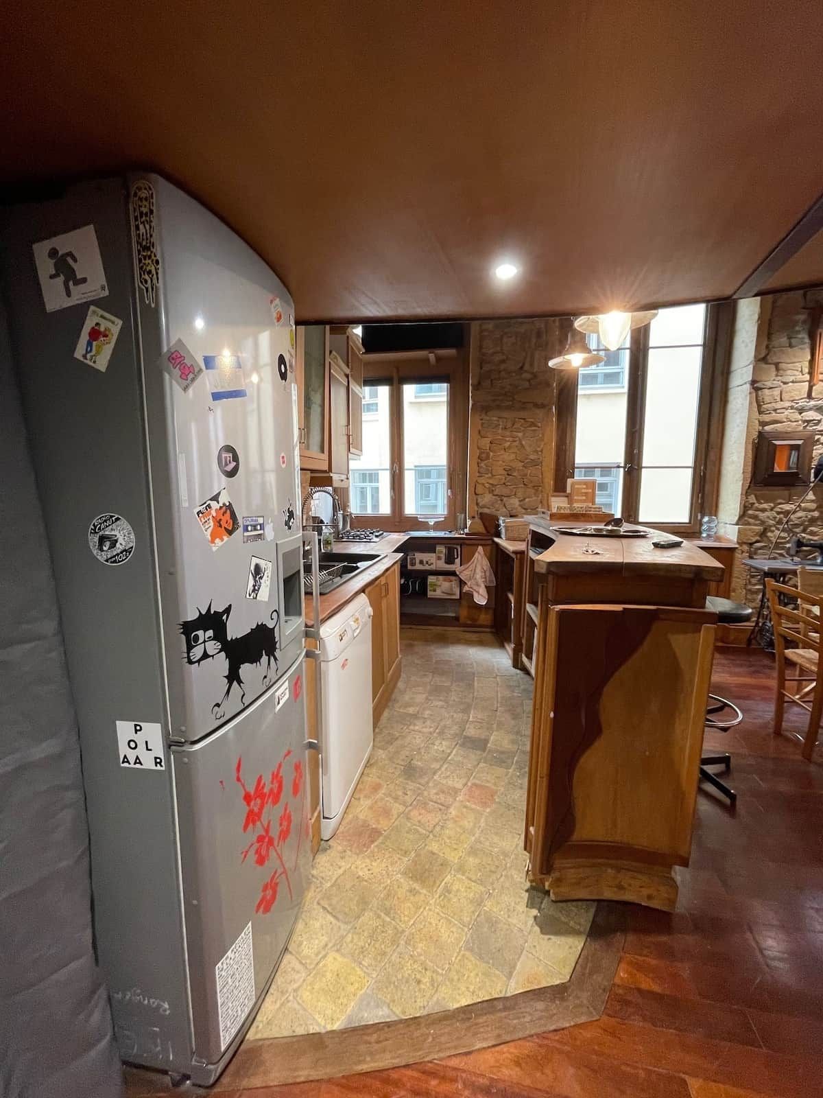 Eine kleine Küche mit Kühlschrank, Geschirrspüler und einer Holzinsel.