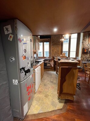 A compact kitchen with a refrigerator, a dishwasher, and a wooden island. - Charming "Heart of Lyon" Apartment with Elevator, A/C & Parking (Lyon)