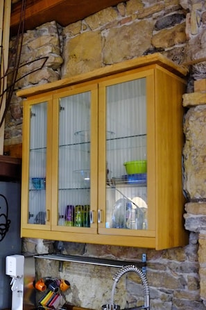 A kitchen with a wooden cabinet, a coffee machine, and a stone wall. - Charming "Heart of Lyon" Apartment with Elevator, A/C & Parking (Lyon)
