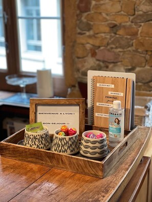 Un plateau en bois avec un panneau indiquant « Bienvenue », un carnet, un stylo et un flacon de gel hydroalcoolique.
