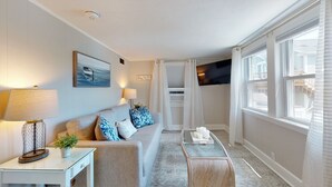 Un salon moderne avec un canapé, deux lampes, une table basse et un téléviseur.