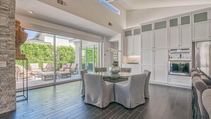 A modern kitchen with white cabinets, a built-in oven, and a large window overlooking a patio area.