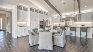 A modern kitchen with white cabinetry, a central island with seating, and pendant lighting.