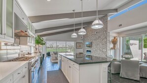A modern kitchen with a central island, pendant lighting, and a stone accent wall.