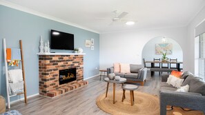 Cozy living space with a brick fireplace, flat-screen TV, and dining area.
