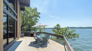 A wooden deck with outdoor furniture and a view of a lake.