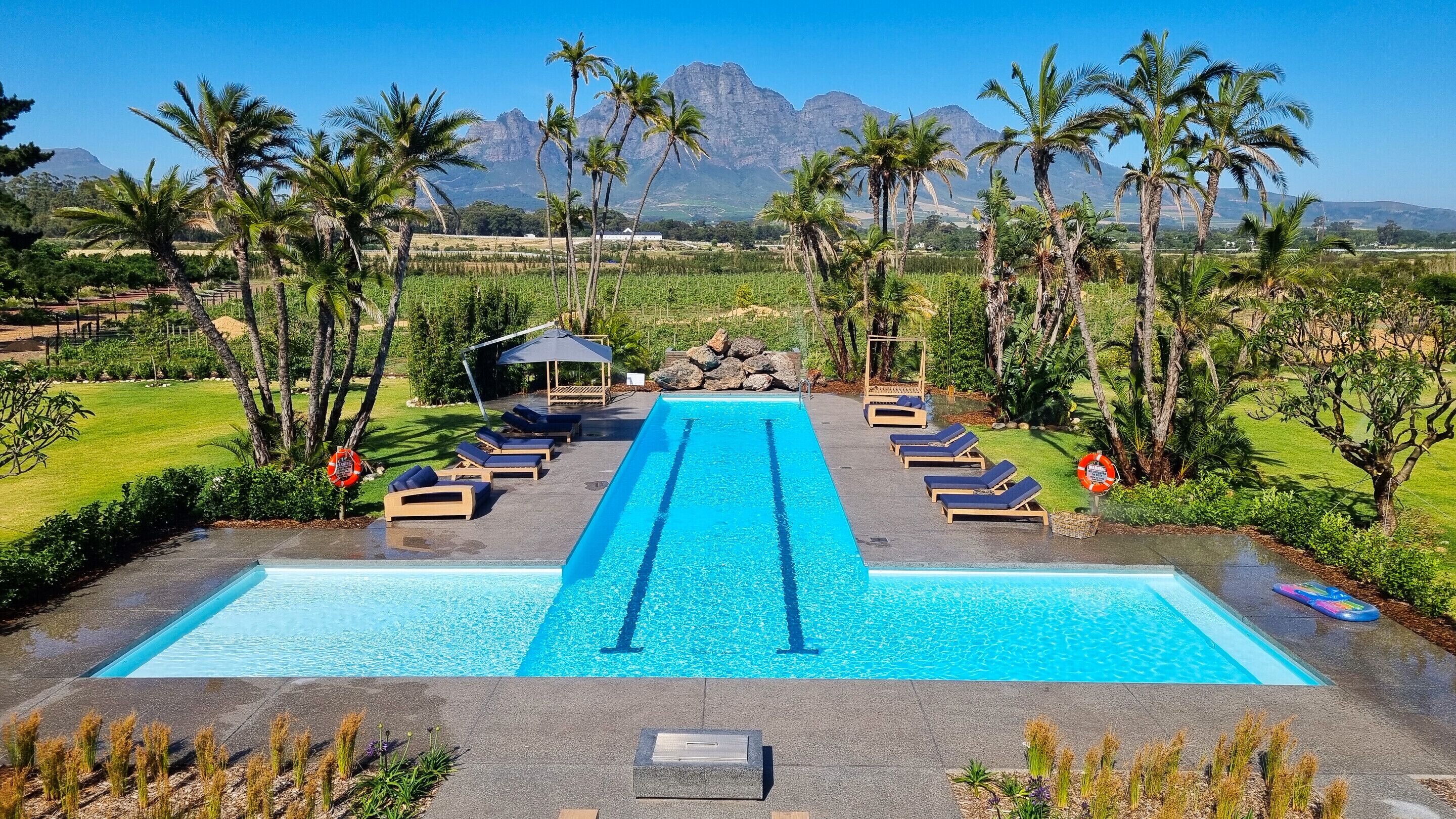 Een buitenzwembad, ligstoelen bij het zwembad