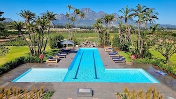 Een buitenzwembad, ligstoelen bij het zwembad