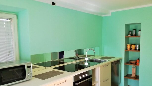 A compact kitchen with a microwave, stove, sink, and storage shelves. - Ambra - Central Apartment in Bergamo (Bergamo)