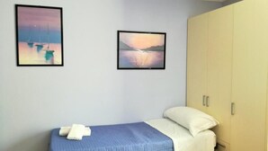 A bedroom with a bed, two framed pictures, and a wardrobe. - Ambra - Central Apartment in Bergamo (Bergamo)