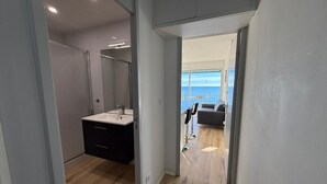 Een moderne badkamer met een grote spiegel, een wastafel en een donker kastje.