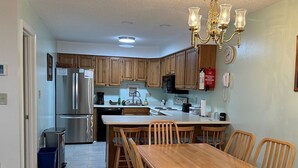 A kitchen with wooden cabinets, a stainless steel refrigerator, a sink, and a dining table with chairs. - Mt Views from #238 Two Bedroom Condo (Lincoln)