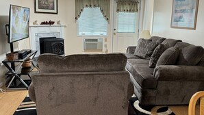 A living room with a fireplace, a sofa, a television, and a fireplace mantel. - Mt Views from #238 Two Bedroom Condo (Lincoln)