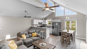 A spacious living room with a gray sofa, wooden coffee table, and a ceiling fan. - Two Decks, Wheelchair Accessible, Large Yard with close beach access.  Sail Away (Oak Island)