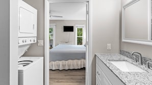 A modern bathroom with a built-in washer and dryer, a large mirror, and a granite countertop sink. - Two Decks, Wheelchair Accessible, Large Yard with close beach access.  Sail Away (Oak Island)
