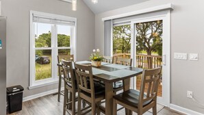 A dining area with a table and chairs, large windows, and a view of the outdoors. - Two Decks, Wheelchair Accessible, Large Yard with close beach access.  Sail Away (Oak Island)