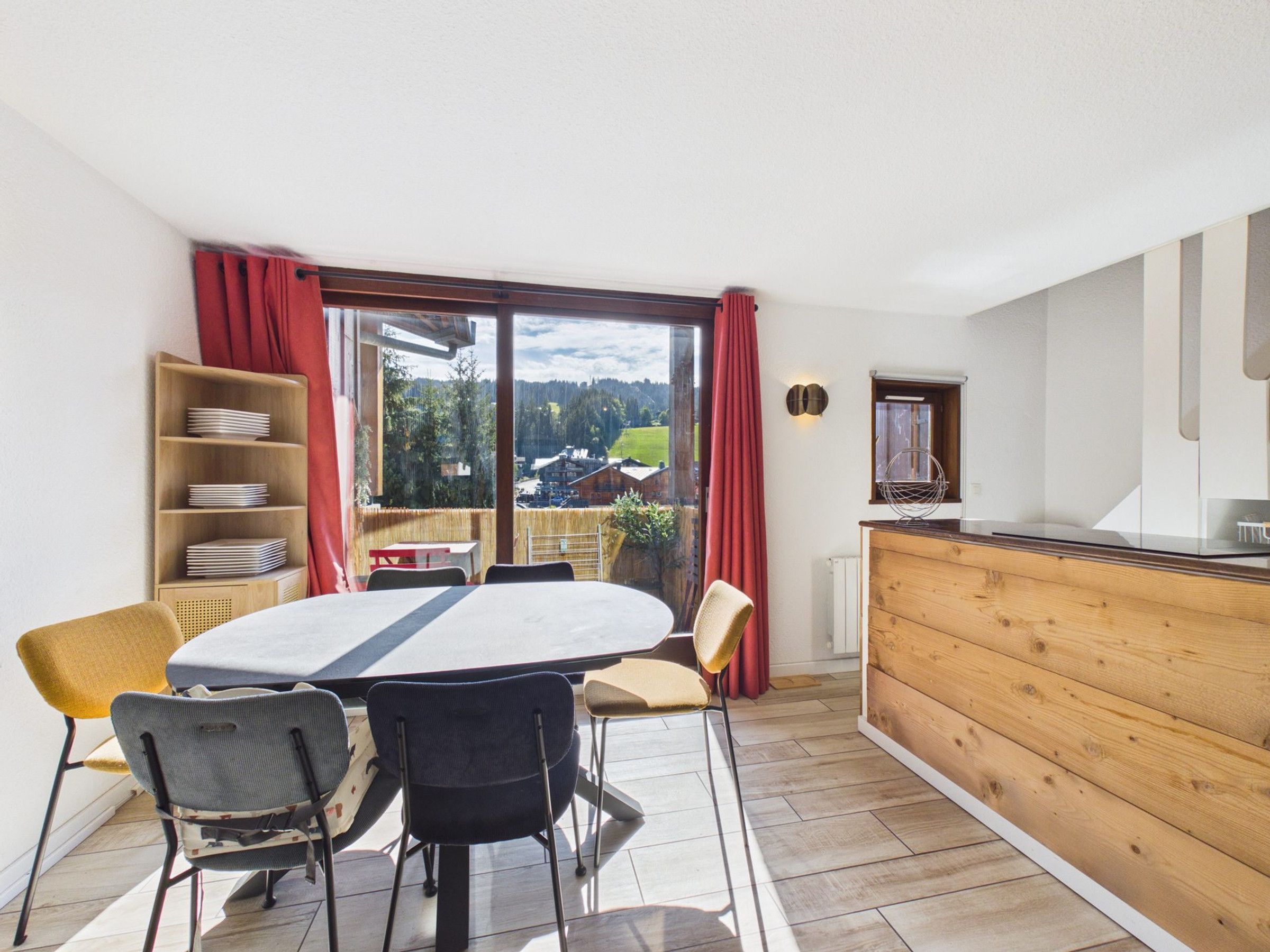 Ein Essbereich mit Tisch und Stühlen, einem Holzbuffet und Blick ins Freie.