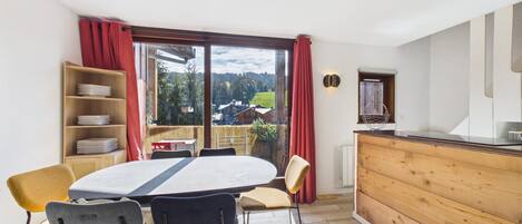 Ein Essbereich mit Tisch und Stühlen, einem Holzbuffet und Blick ins Freie.