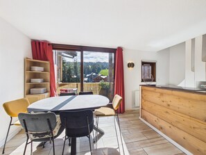 A dining area with a table and chairs, a wooden buffet, and a view of the outdoors.