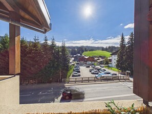 A parking lot with cars, a building with a green roof, and a clear sky.